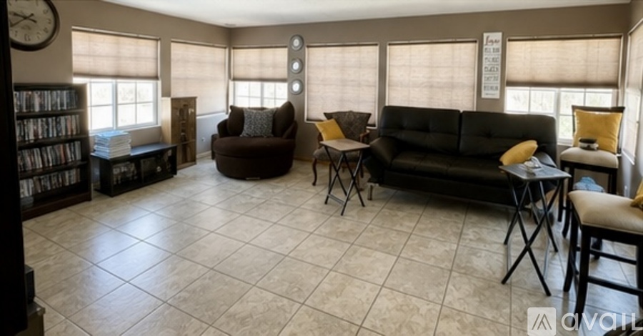A living room with a black couch, a brown armchair, and a coffee table.
