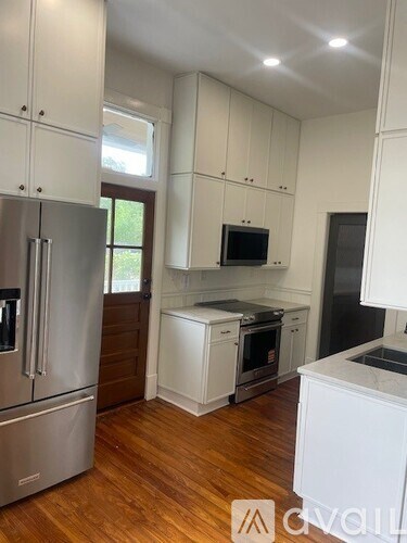 A kitchen with white cabinets and a wooden floor.