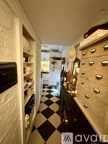 A white refrigerator is in a kitchen with black countertops.