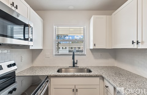 A kitchen with a granite countertop and a window with blinds.