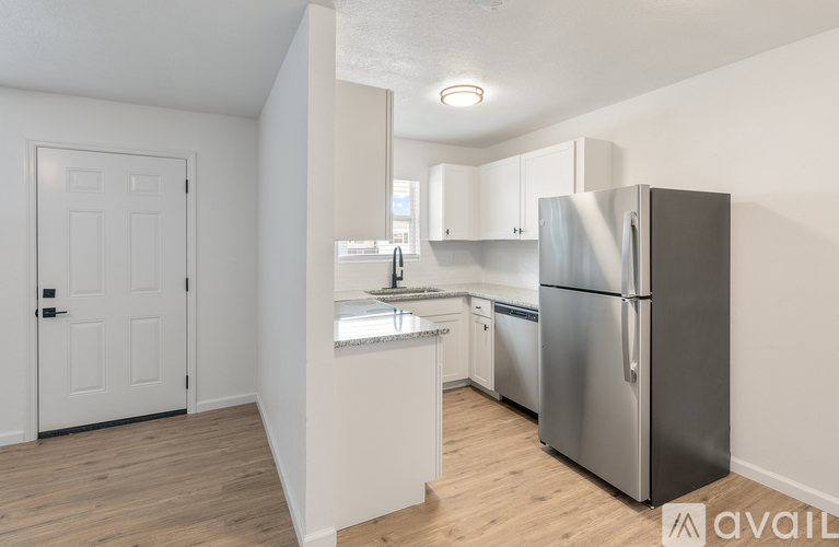 A kitchen with a refrigerator, sink, and cabinets.
