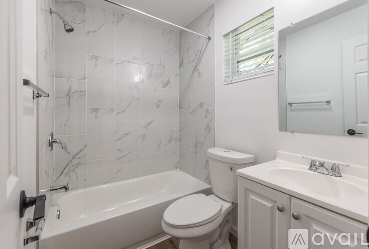 A white bathroom with a marble tile shower.
