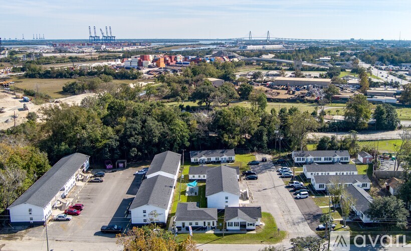 A bird's eye view of a parking lot with a few cars and a building with a white roof.