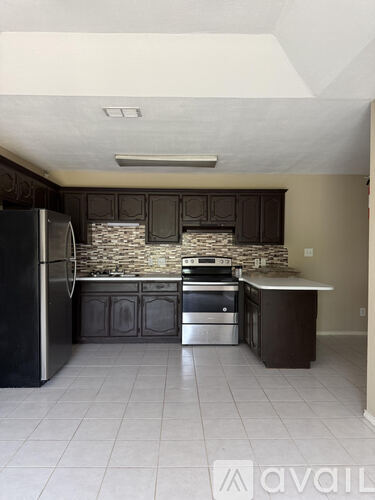 A kitchen with a black fridge and stove top oven.