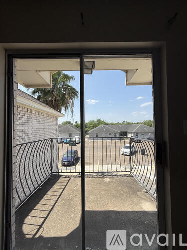 A view from inside a building looking out to a parking lot with cars and a fence.