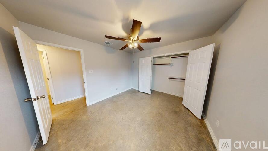 A room with a ceiling fan and two doors, one of which is open.