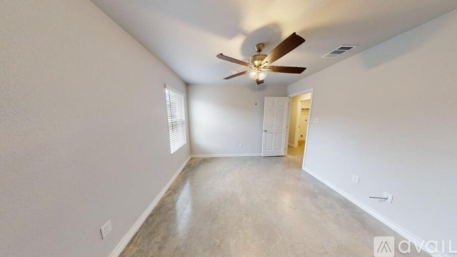A spacious room with a ceiling fan and a door leading to another room.