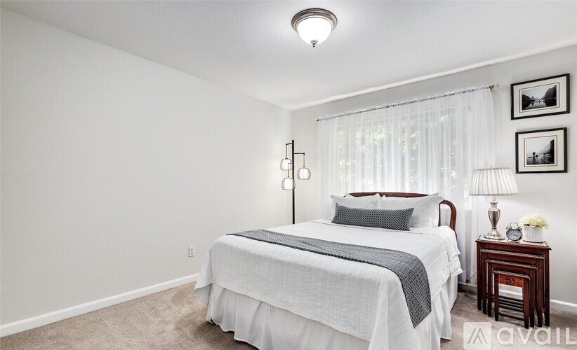 A bedroom with a bed, nightstand, and pictures on the wall.