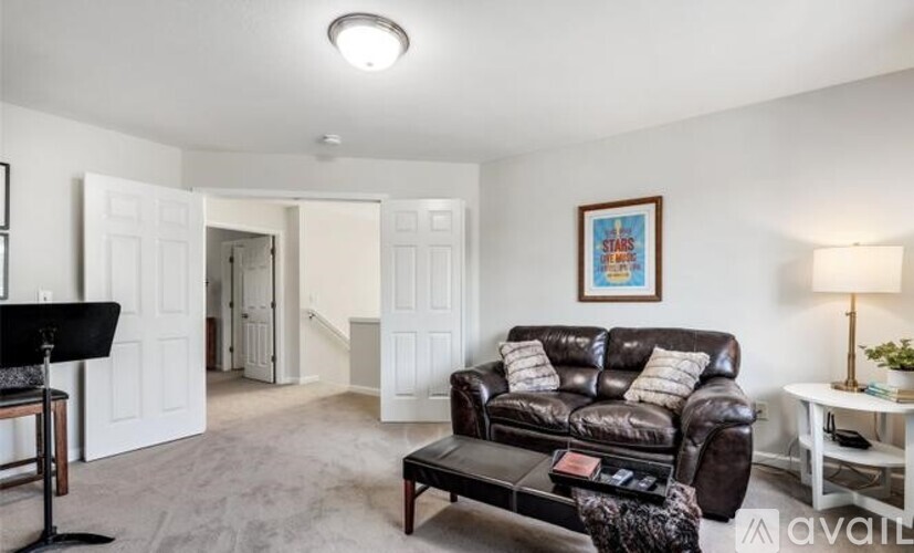 A living room with a brown leather couch and a framed picture on the wall.