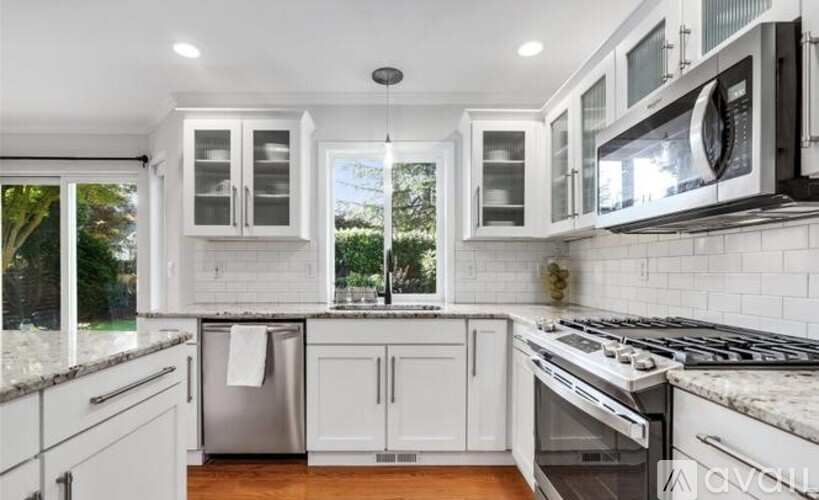 A modern kitchen with white cabinets and stainless steel appliances.
