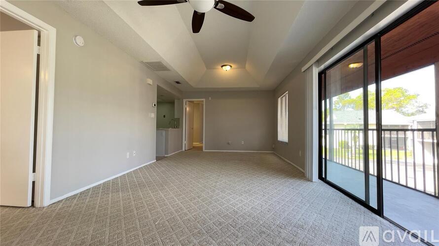 A spacious room with a ceiling fan and sliding glass doors.