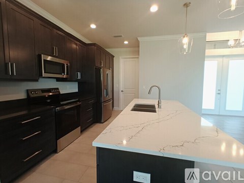 A kitchen with dark brown cabinets and a white marble countertop.