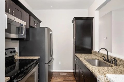 A kitchen with black appliances and a granite countertop.