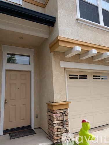 A house with a brown door and a brick pillar.
