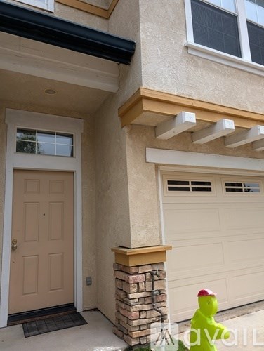 A house with a brown door and a brick pillar.