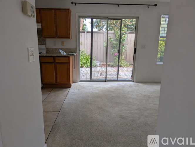 A room with a carpeted floor and a sliding glass door leading to a backyard.