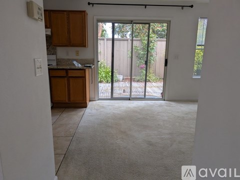 A room with a carpeted floor and a sliding glass door leading to a backyard.