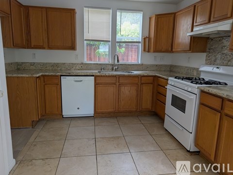 A kitchen with wooden cabinets and a white dishwasher and oven.