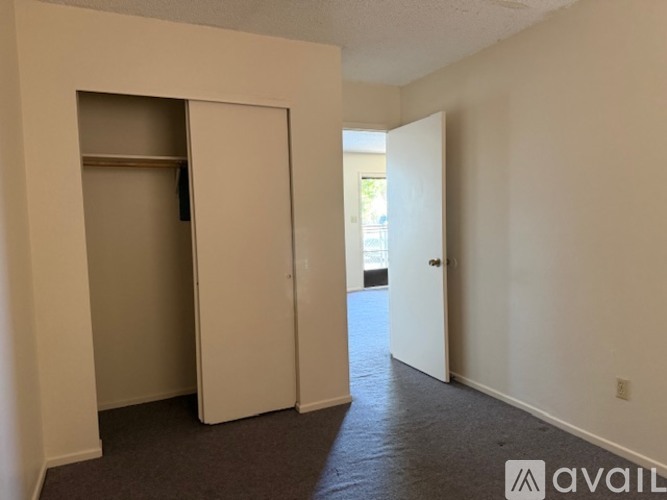 A room with a carpeted floor and two open doors.