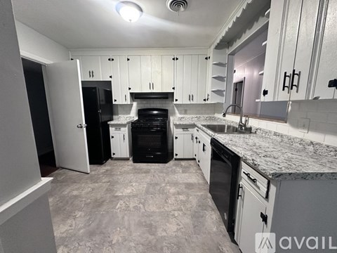 A kitchen with black appliances and white cabinets.