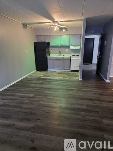 A kitchen area with a black fridge and white cabinets.