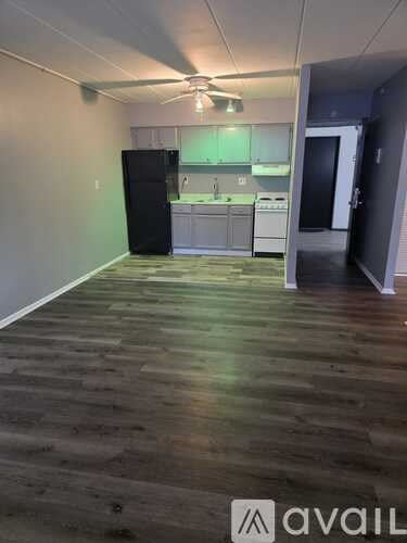 A kitchen area with a black fridge and white cabinets.