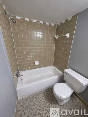 A bathroom with a white tub, toilet, and tiled walls.