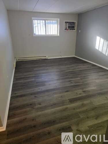 A room with wooden flooring and a window.