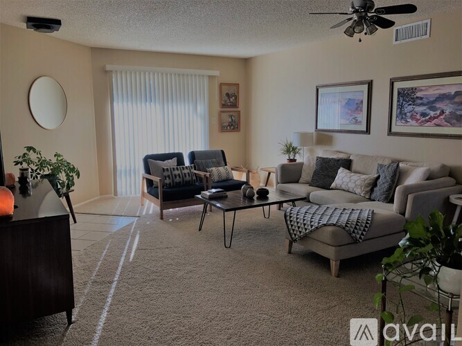 A living room with a grey couch, a coffee table, and a ceiling fan.
