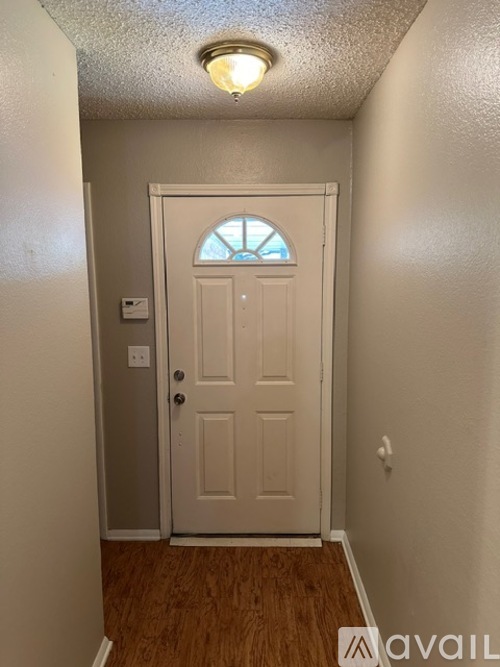 A white door with a window above it in a hallway.