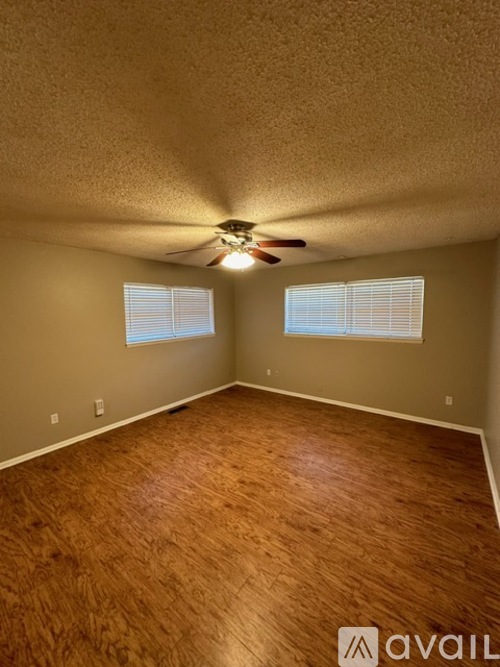 A room with wooden flooring and a ceiling fan.