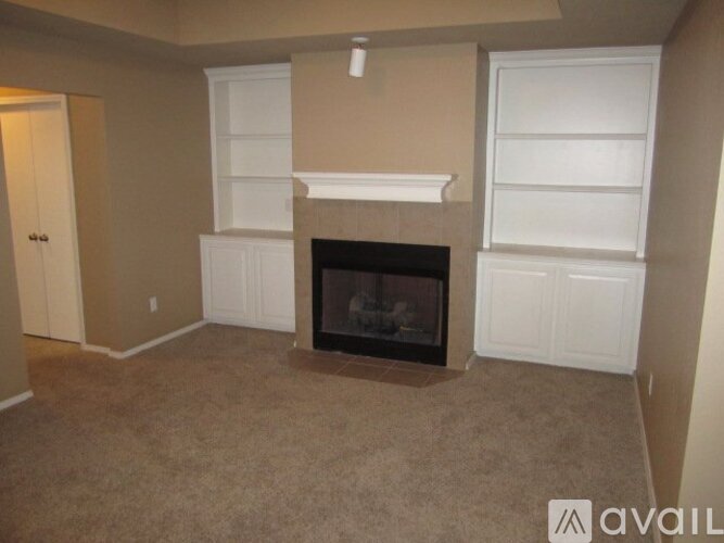 A living room with a fireplace and built-in shelves.