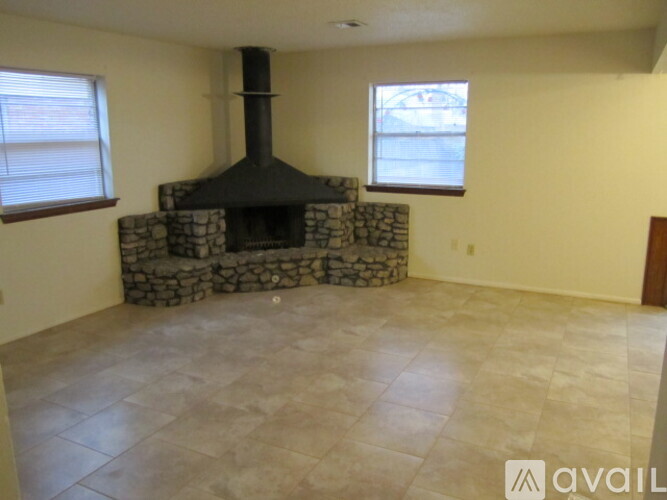 A stone fireplace in a room with tile flooring and two windows.