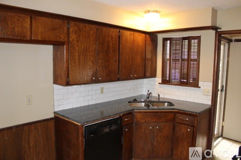 A kitchen with wooden cabinets and a black dishwasher.