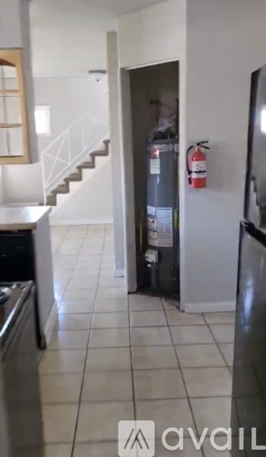 A kitchen with a white tile floor and a stainless steel dishwasher.