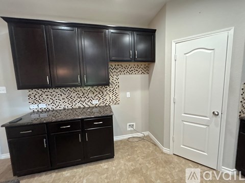 A kitchen area with black cabinets and a white door.