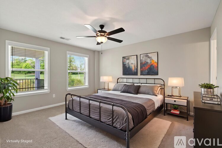 A bedroom with a large bed, a ceiling fan, and two lamps.