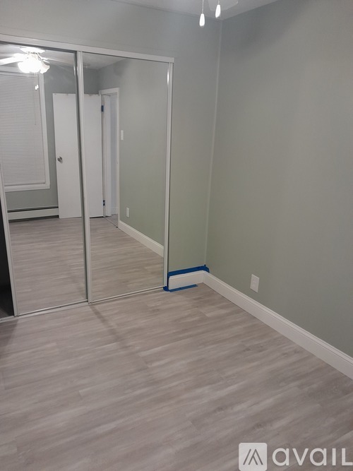 A room with a mirrored door and wooden flooring.