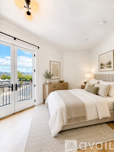 A bedroom with a large bed and a view of the outside through the sliding glass doors.