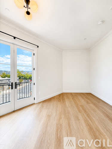 A room with wooden flooring and a sliding glass door leading to a balcony.