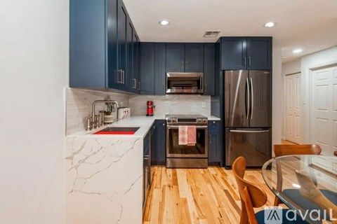 A kitchen with dark blue cabinets and a marble countertop.