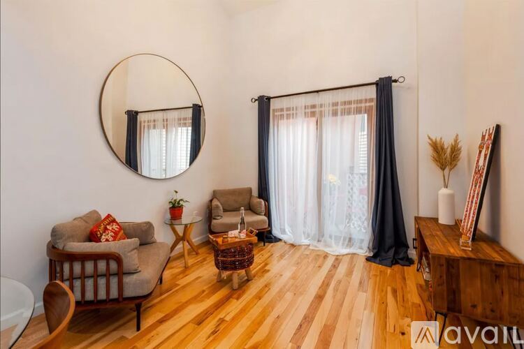 A living room with a sofa, a table, a mirror, and a window with curtains.