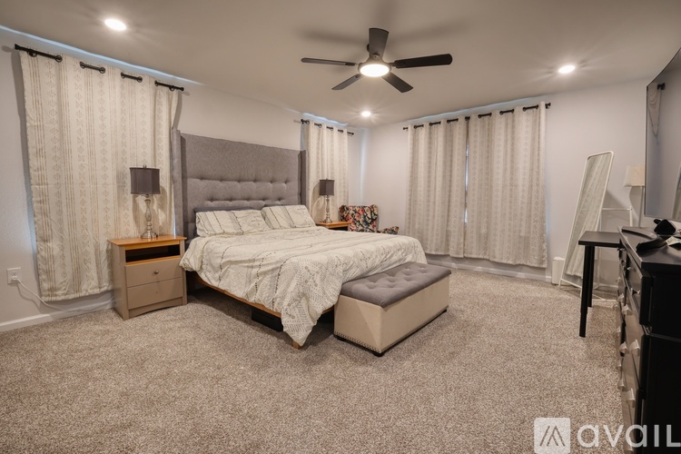 A bedroom with a large bed and a ceiling fan.
