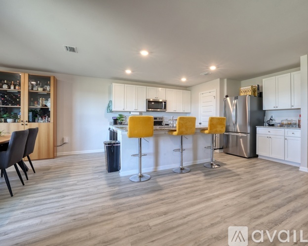 A modern kitchen with white cabinets and a wooden floor.