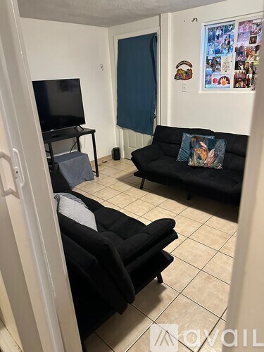 A living room with a black couch and a television.