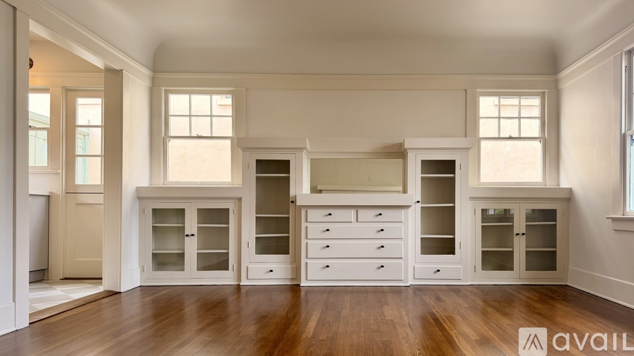 A spacious kitchen with white cabinets and a wooden floor.