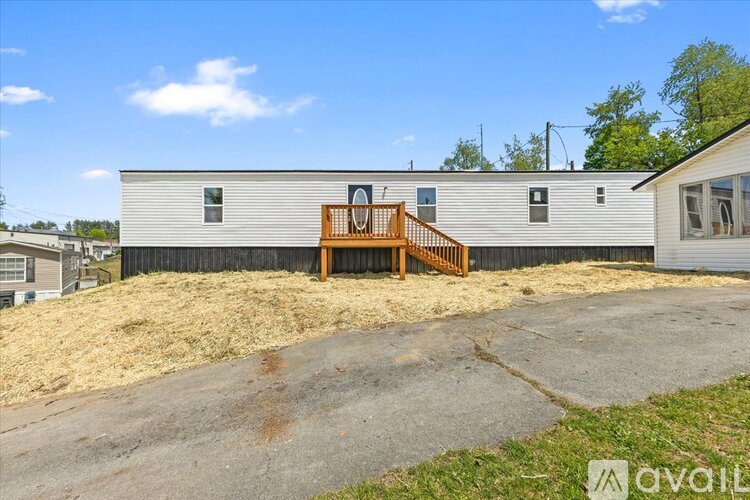 A mobile home with a wooden deck and a fence.