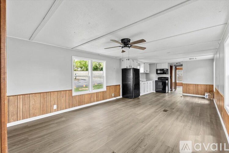 A spacious room with wooden flooring and a ceiling fan.