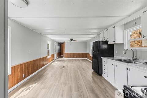 A kitchen with white cabinets and a black refrigerator.