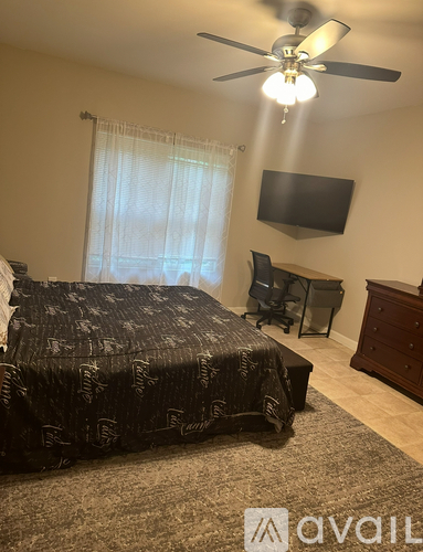 A bedroom with a bed, desk, and television.